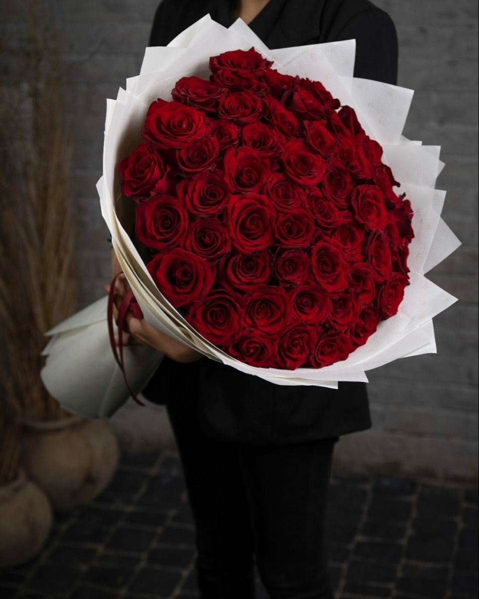Bouquet of red roses held by a person against a blurred background