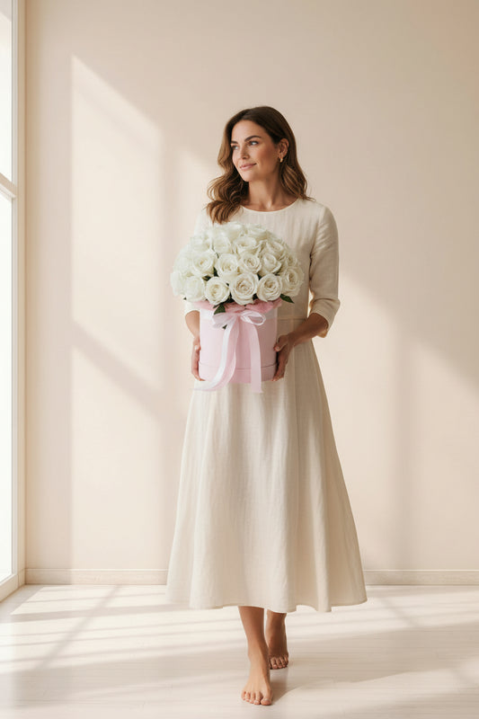 Woman holding a box of white roses in a softly lit room.