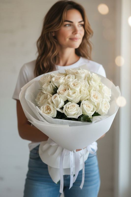 Woman holding a bouquet of white roses against a neutral background