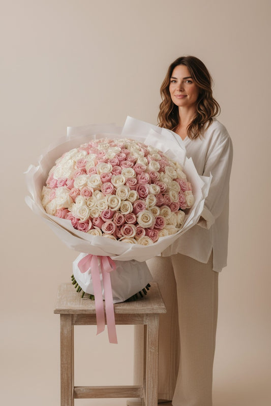Woman holding a large bouquet of pink and white roses on a beige background