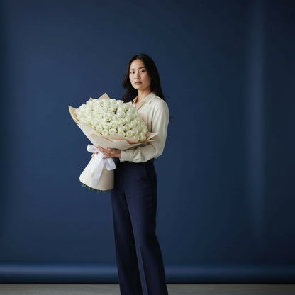 Woman holding a large bouquet of white flowers against a dark blue background