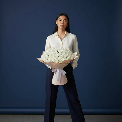 Woman holding a large bouquet of white flowers against a blue background