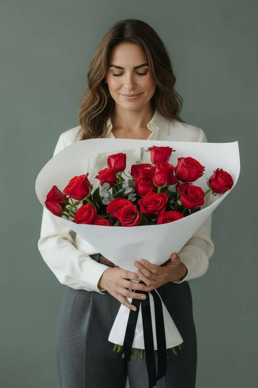 Woman holding a bouquet of red roses against a plain background