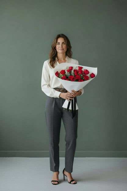 Woman holding a bouquet of red roses against a plain background