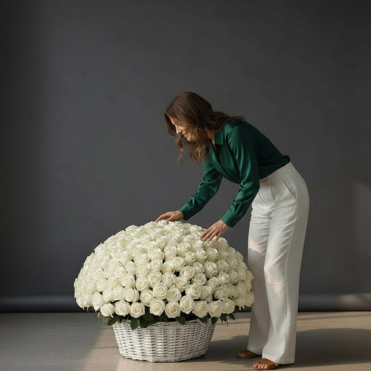 Woman arranging a large bouquet of white flowers in a wicker basket against a dark background