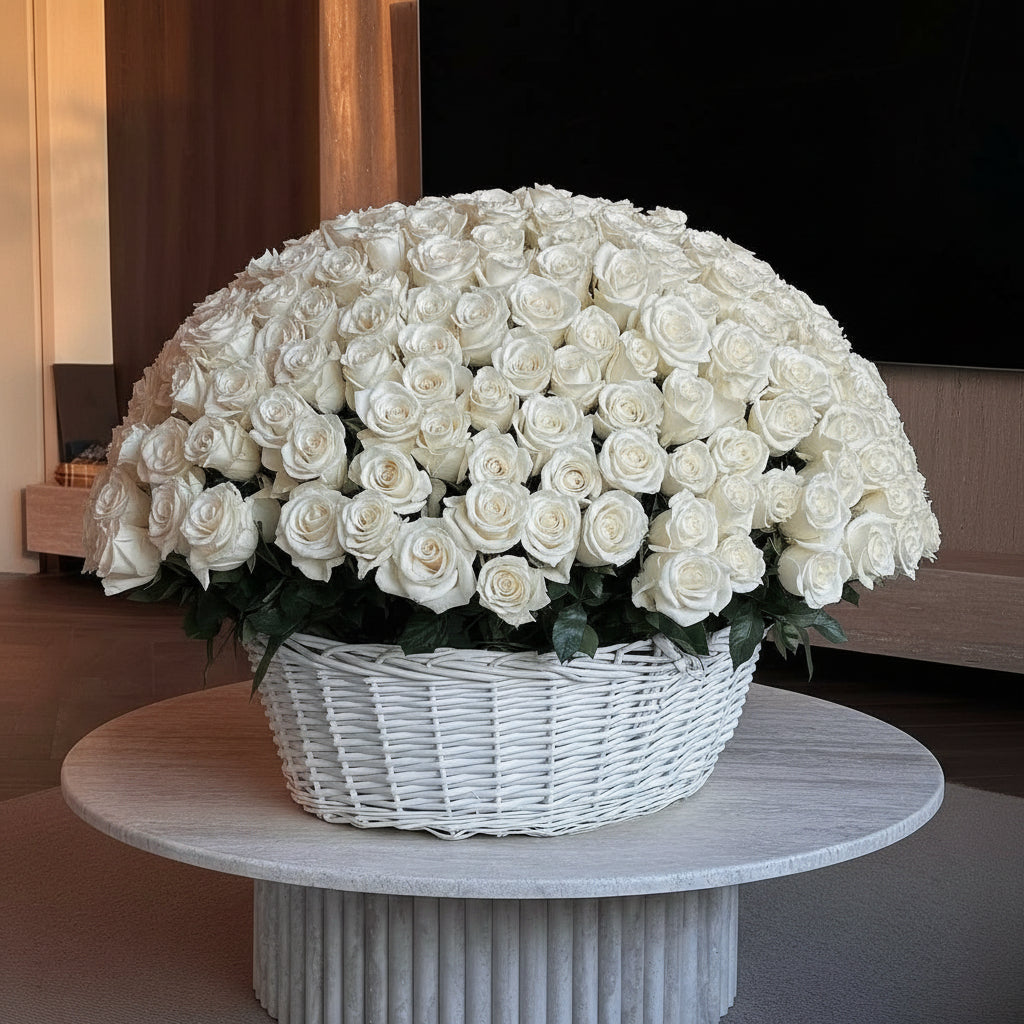 Large arrangement of white roses in a wicker basket on a round table.