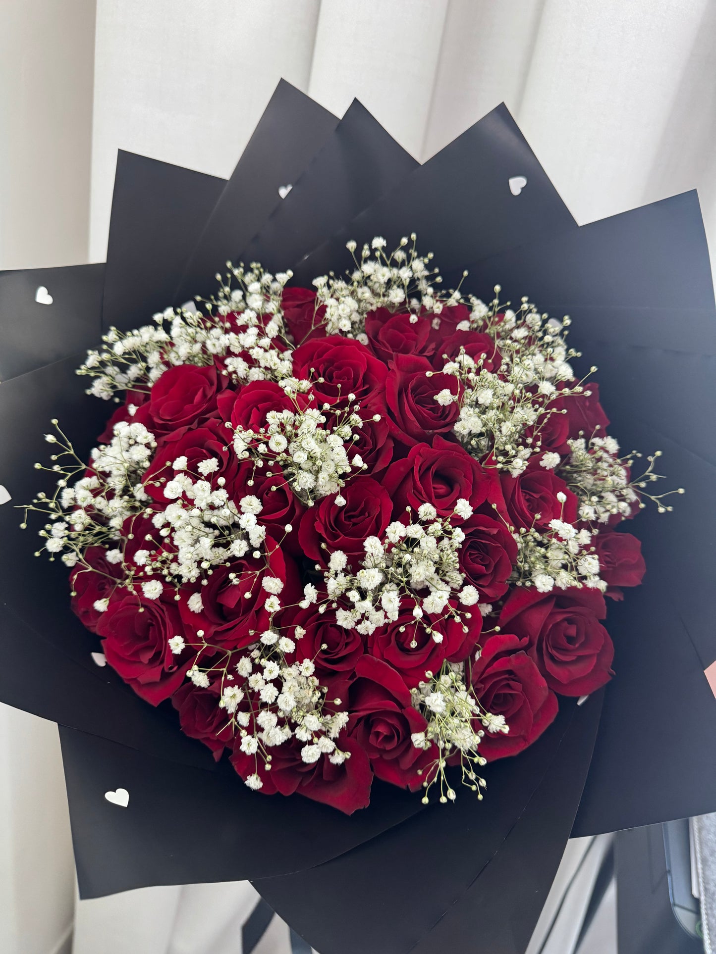 Bouquet of red roses with white baby's breath wrapped in black paper