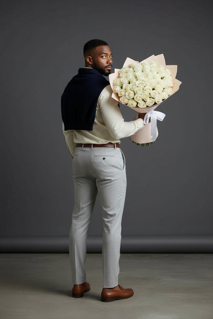Man holding a large bouquet of white flowers against a gray background