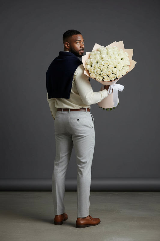 Man holding a large bouquet of white flowers against a gray background