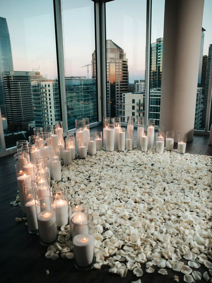 Candles arranged on pebbles with a cityscape view through large windows.