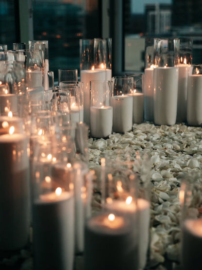 Candles in glass holders on a pebble surface with blurred background