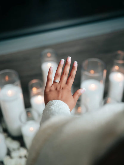 Hand with a ring in front of lit candles
