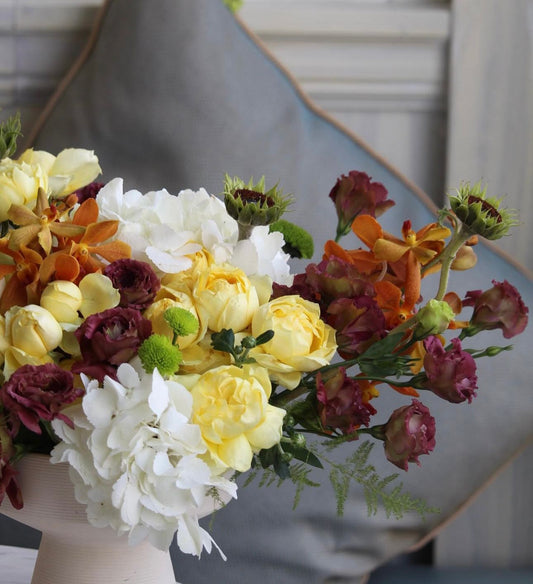 Bouquet of flowers with yellow, white, and purple colors in a vase.