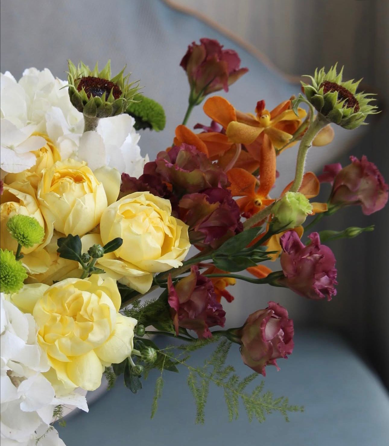 Bouquet of colorful flowers including yellow, pink, and green on a blue surface.