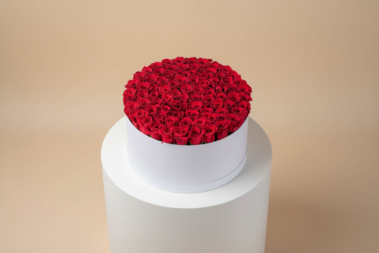 Red rose arrangement in a white box on a beige background