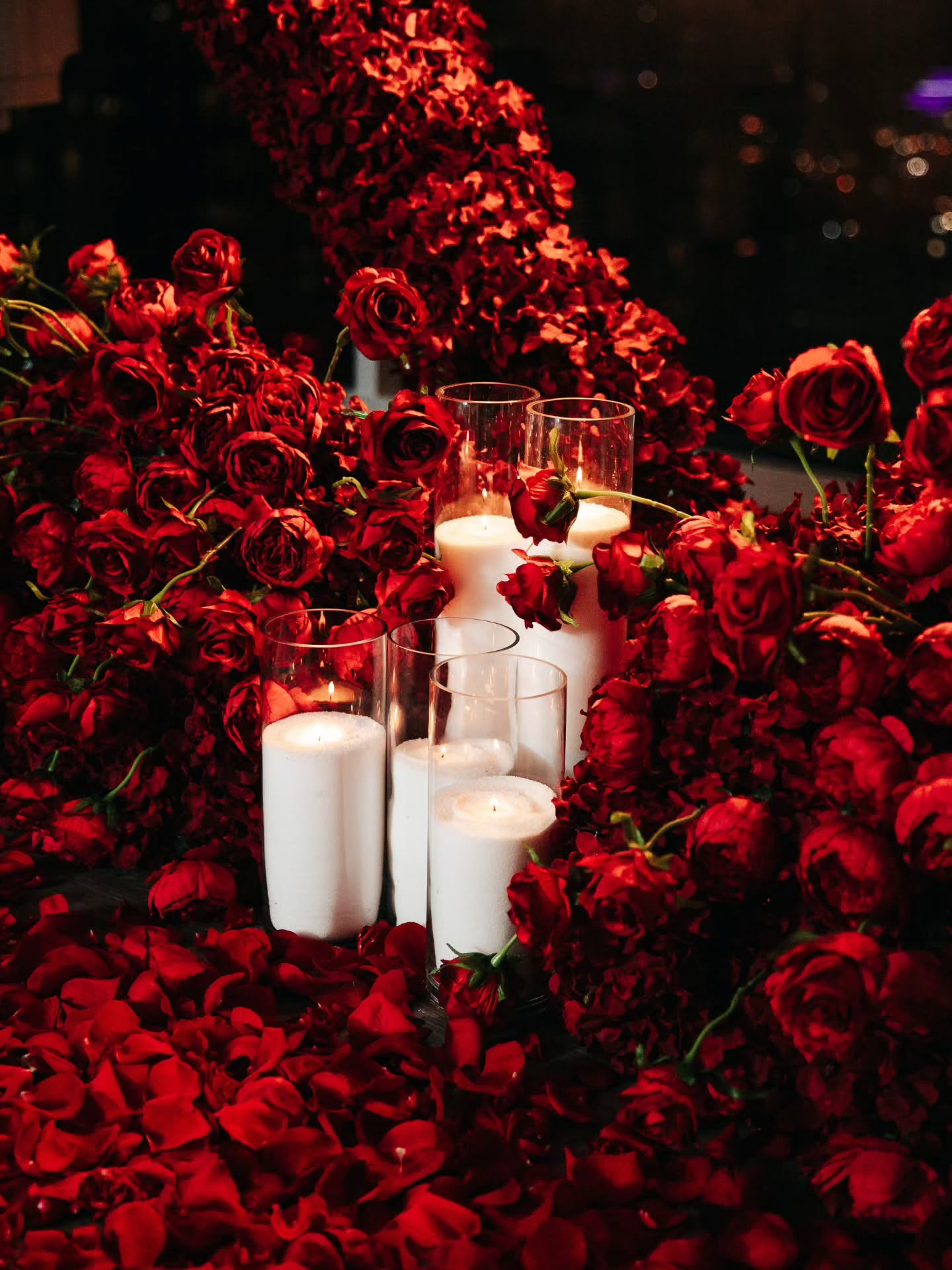Decorative setup with red roses and white candles on a dark background