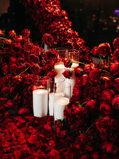 Decorative setup with red roses and white candles on a dark background