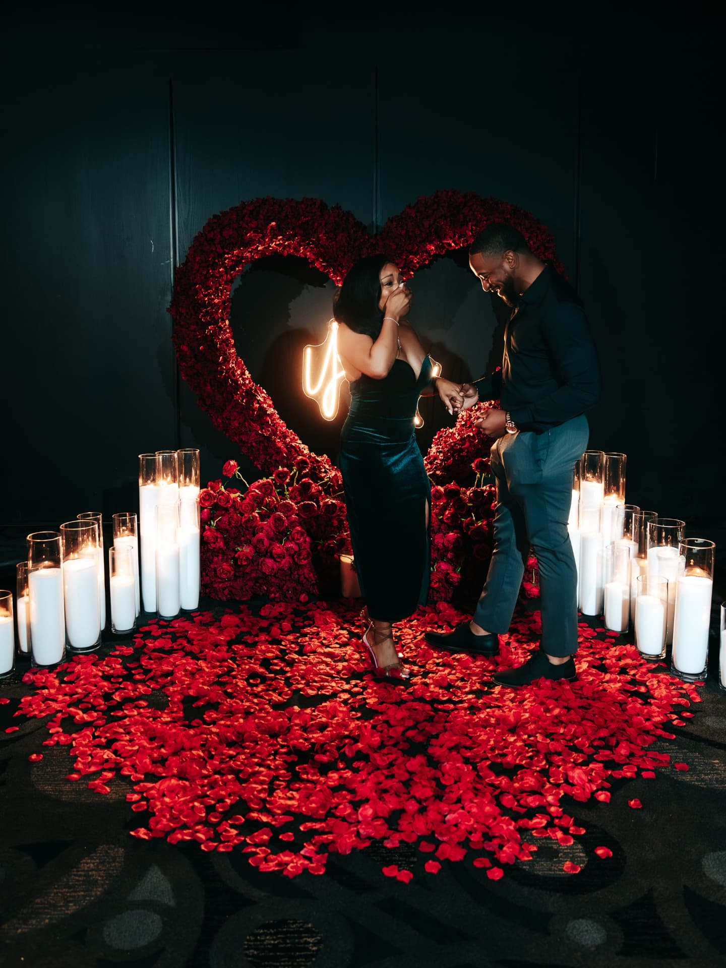 Couple in love surrounded by candles and red flowers on a dark background
