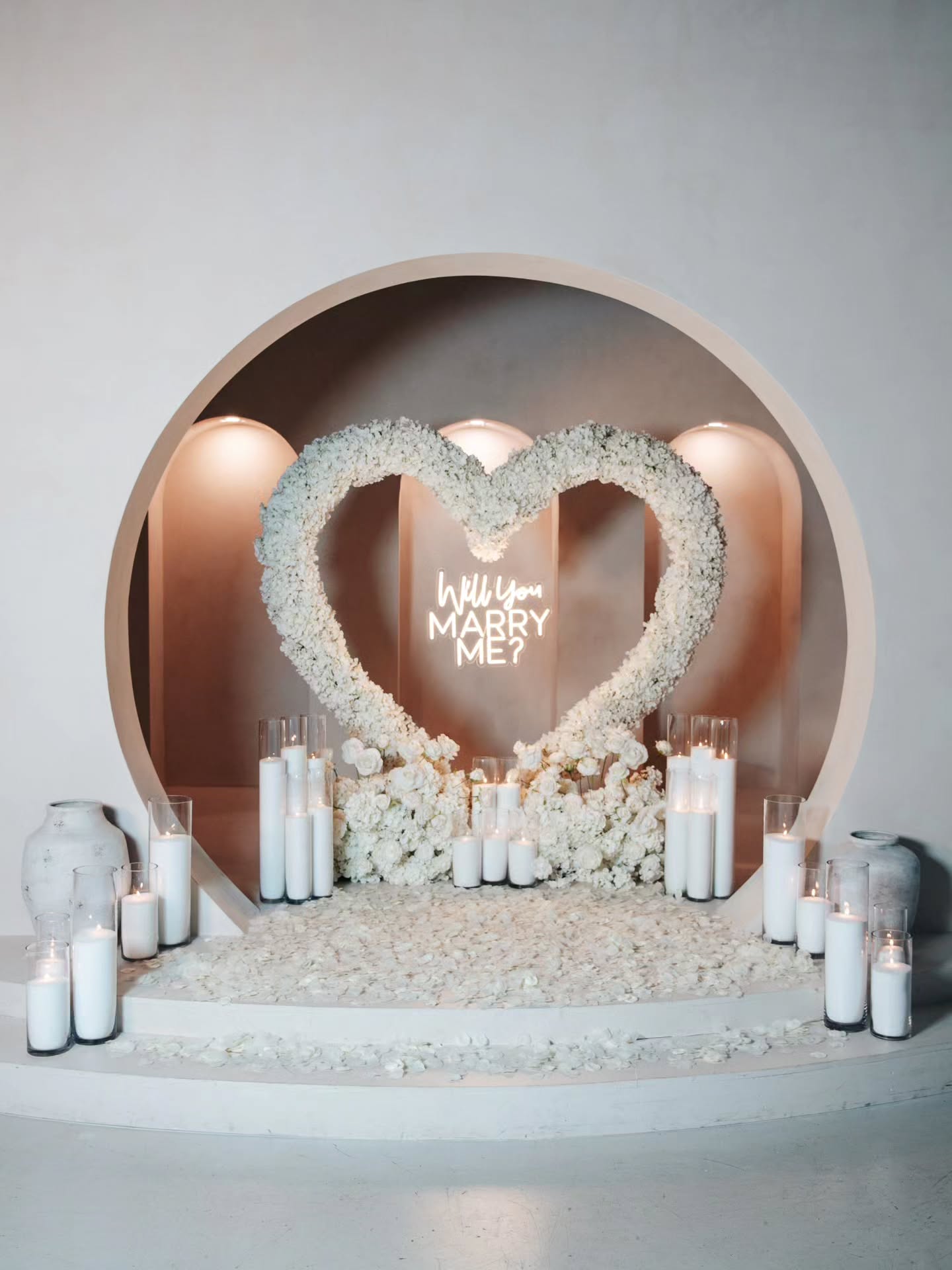 Heart-shaped floral arrangement with candles in a decorative archway