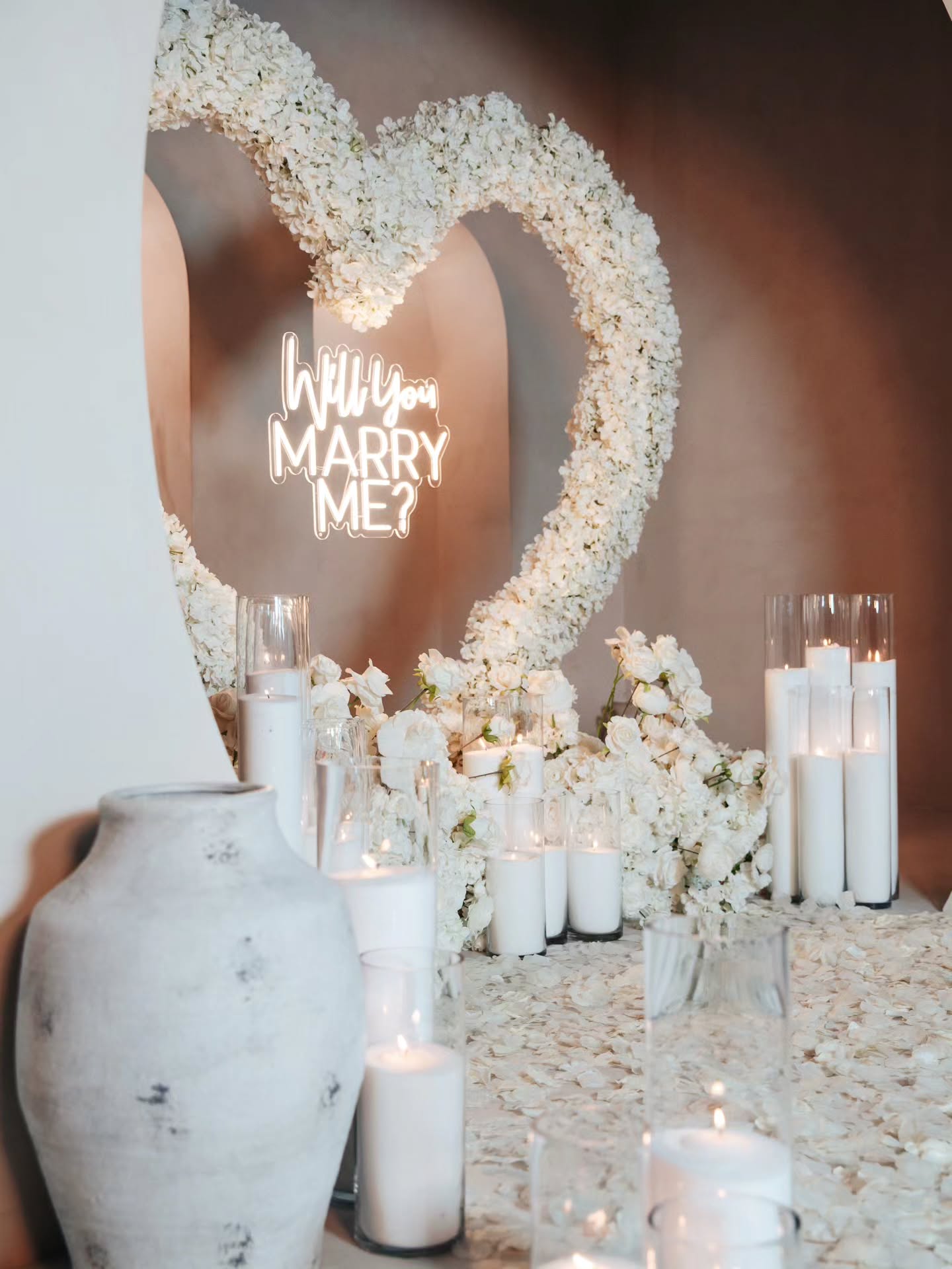 Decorative setup with flowers, candles, and a heart-shaped arrangement with 'Will You Marry Me?' text.