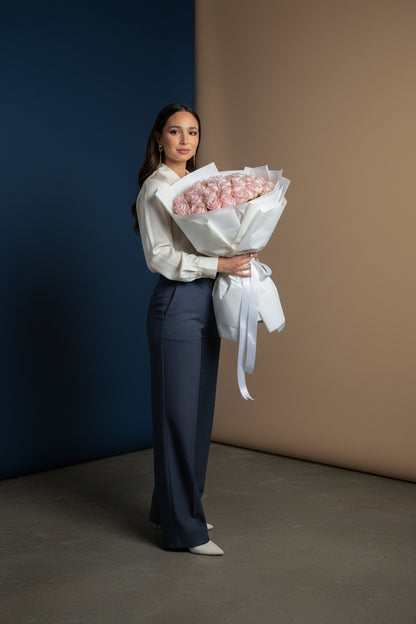 Woman holding a bouquet of pink roses against a neutral background