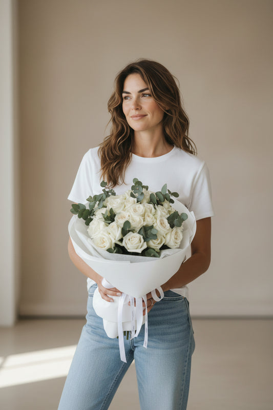 Woman holding a bouquet of white flowers against a neutral background