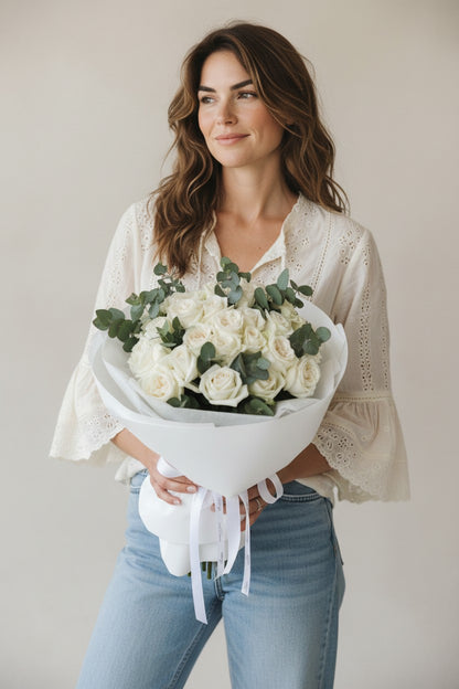 Woman holding a bouquet of white flowers against a plain background