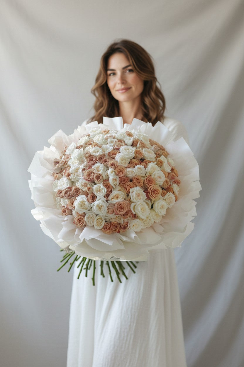 Woman holding a large bouquet of white and pink roses against a plain background