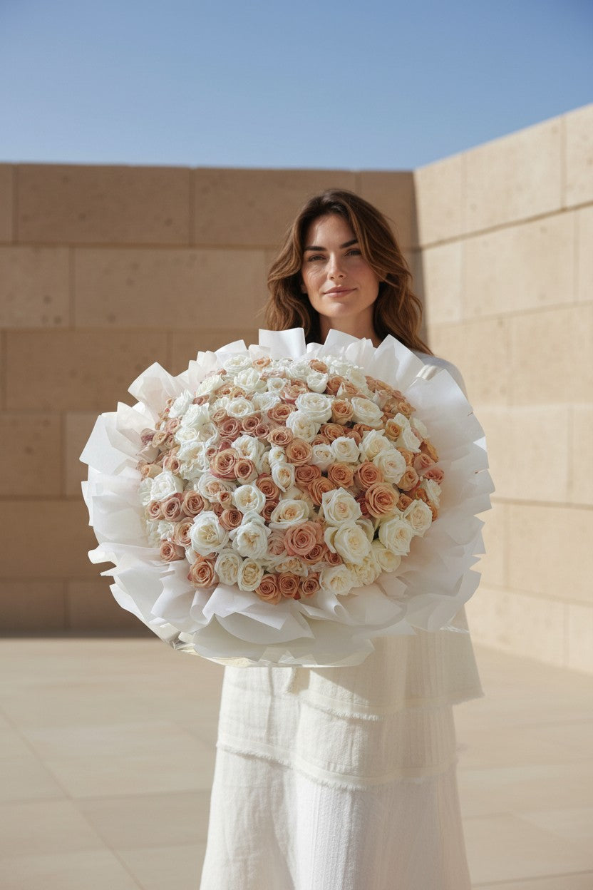 Woman holding a large bouquet of white and pink roses against a plain background