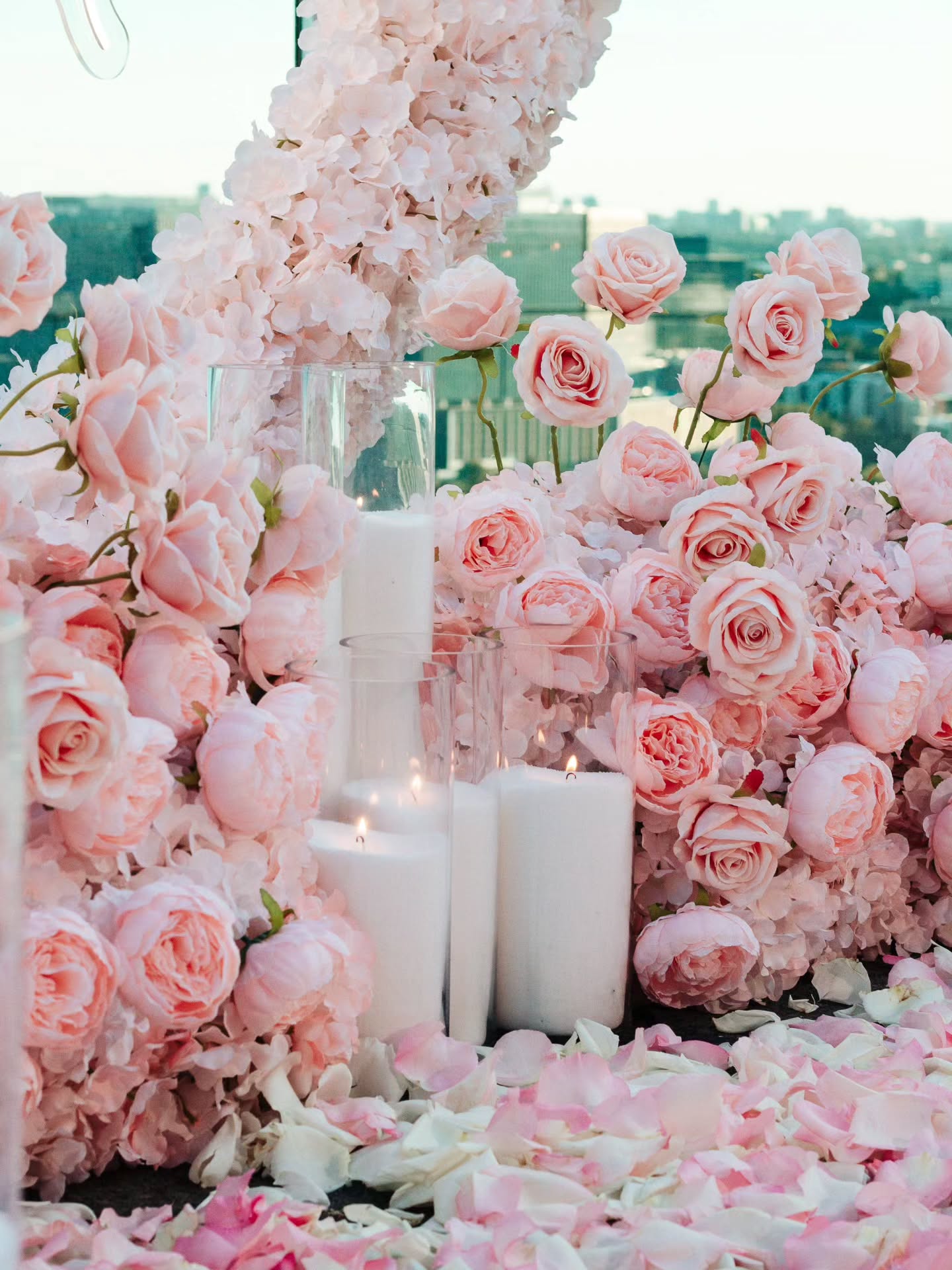 Decorative setup with pink roses and candles in a floral archway.