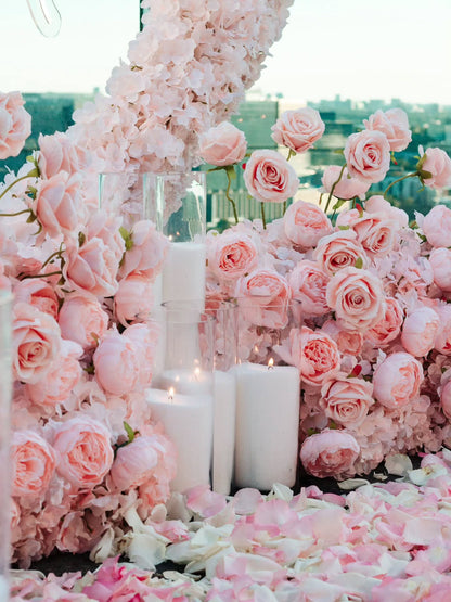 Decorative setup with pink roses and candles in a floral archway.