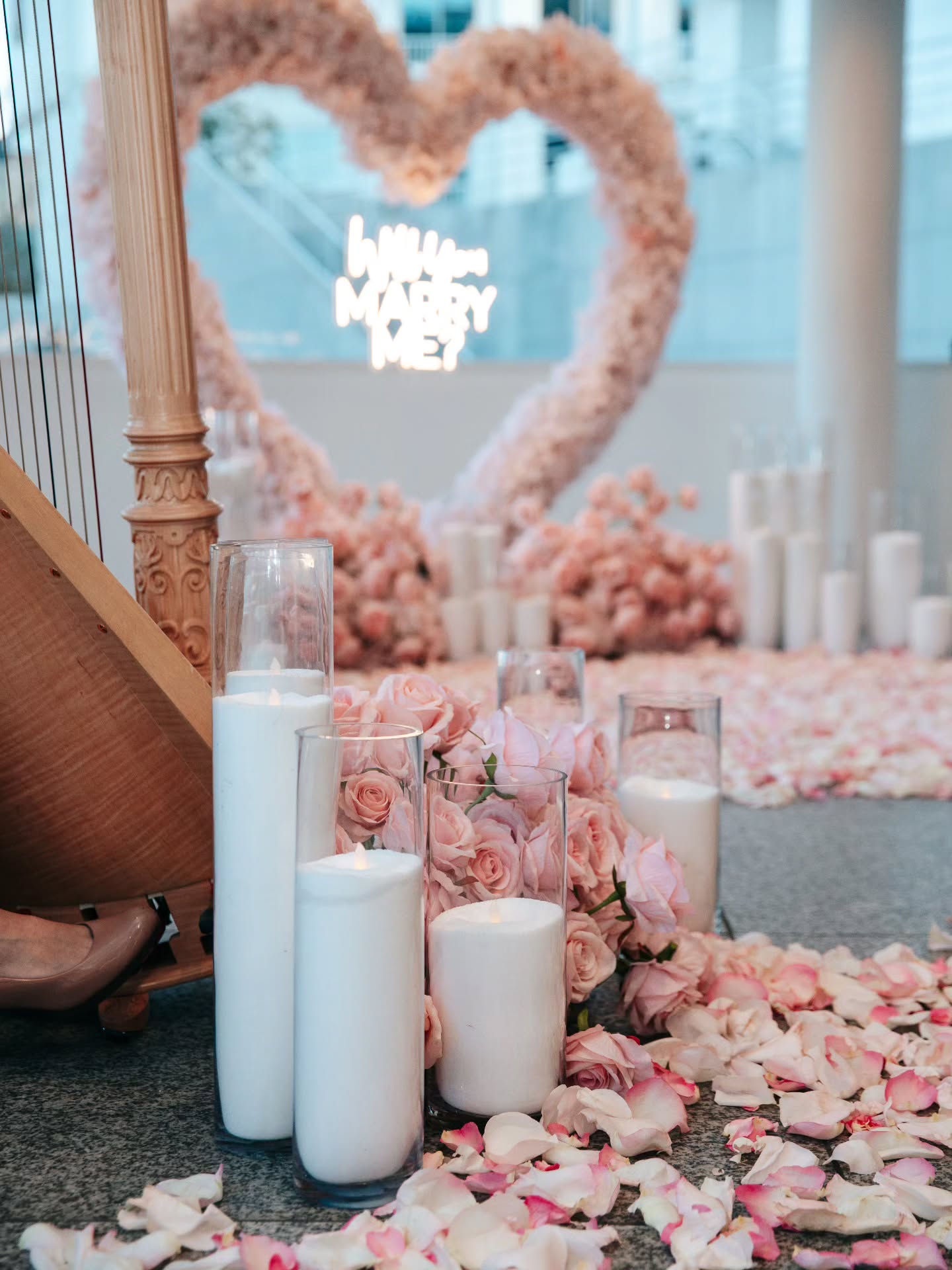 Decorative setup with candles, flowers, and a heart-shaped arch in a room.