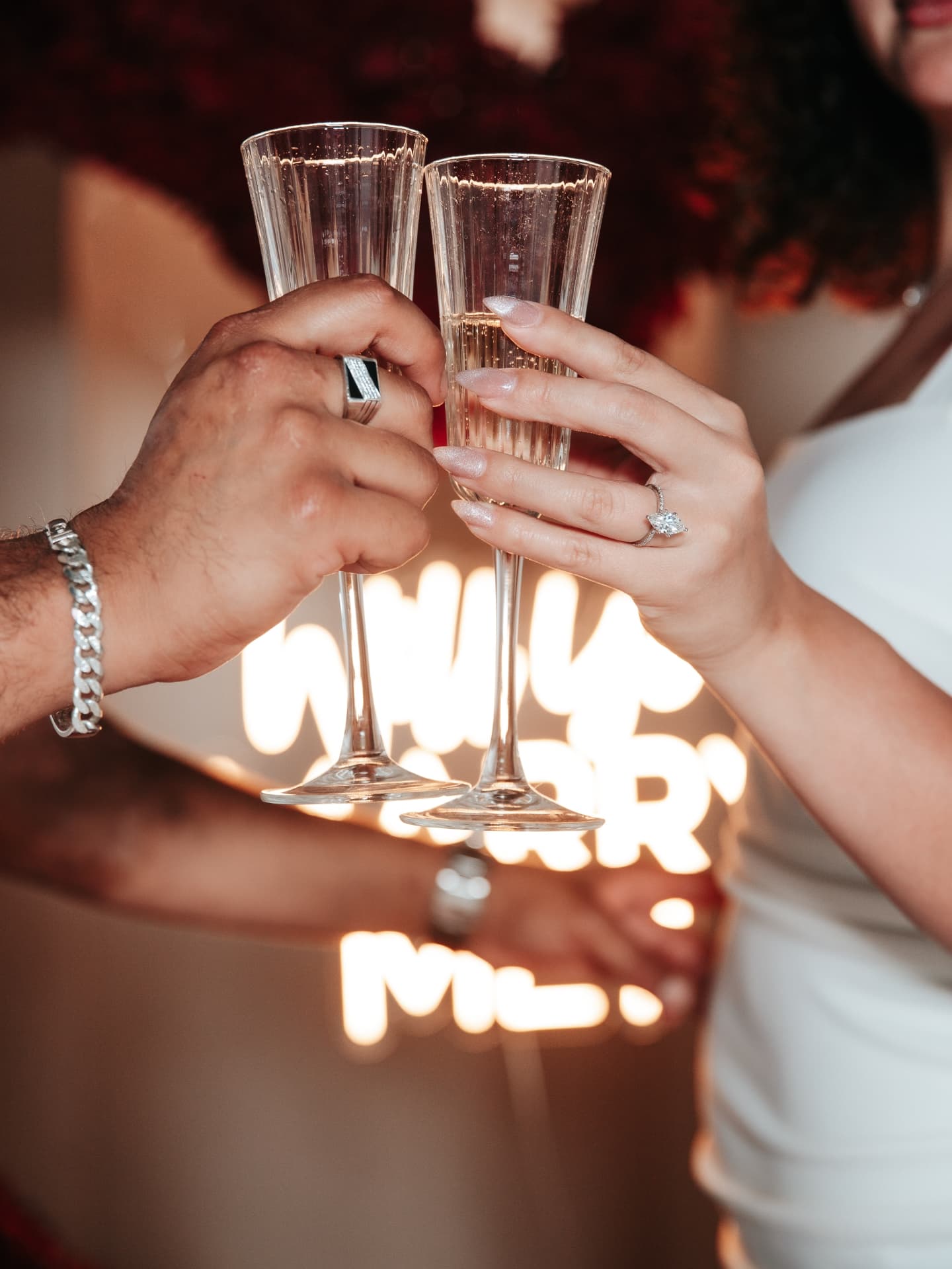 Two people clinking champagne glasses with blurred lights in the background