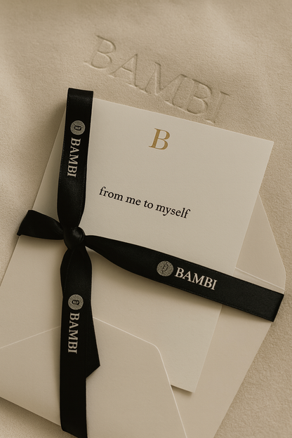 Gift box with black ribbon and card on a beige background, featuring the brand 'Bambi'.