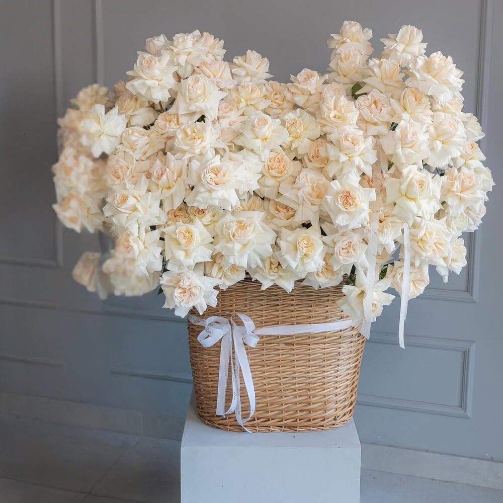 Basket of white flowers on a white pedestal against a gray wall