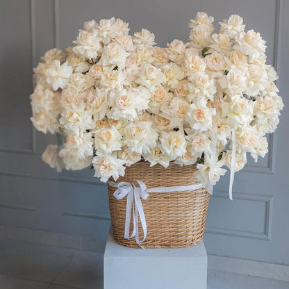 Basket of white flowers on a white pedestal against a gray wall