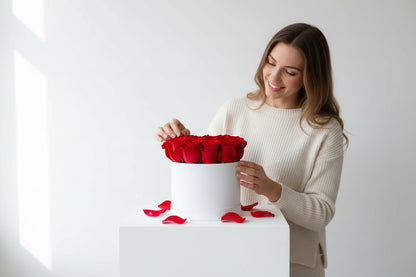 Woman opening a white box filled with red roses on a white background