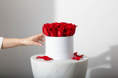 White box with red roses on a marble surface against a gray background