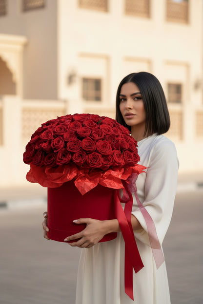 Woman holding a large red box of roses in an urban setting