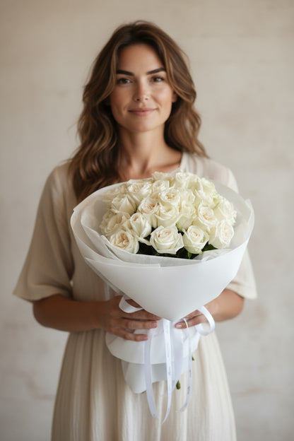 Woman holding a bouquet of white roses against a plain background