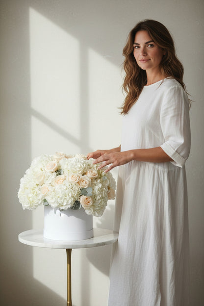 Woman in a white dress holding a bouquet of flowers in a softly lit room.