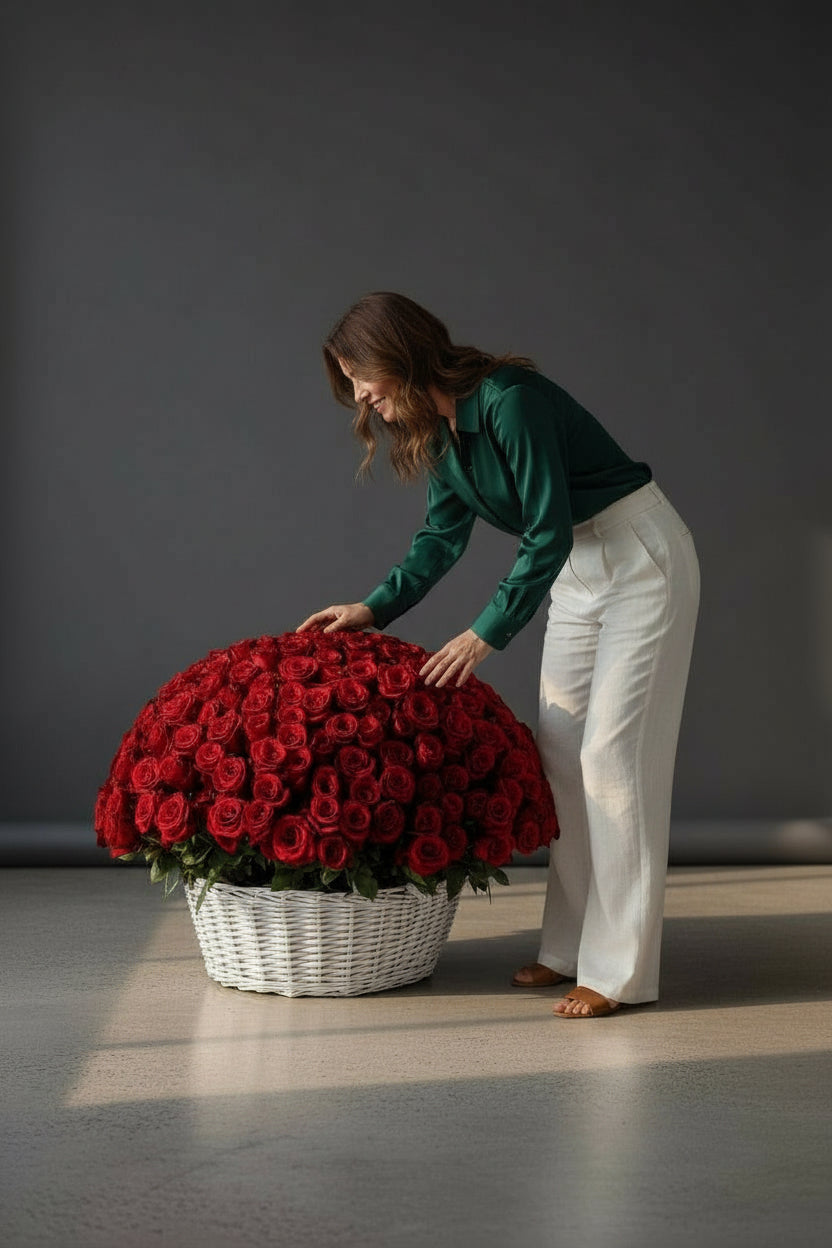 Woman interacting with a large basket of red roses on a gray floor.