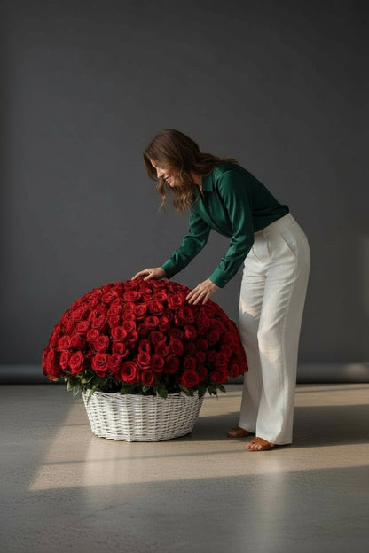 Woman interacting with a large basket of red roses on a gray floor.
