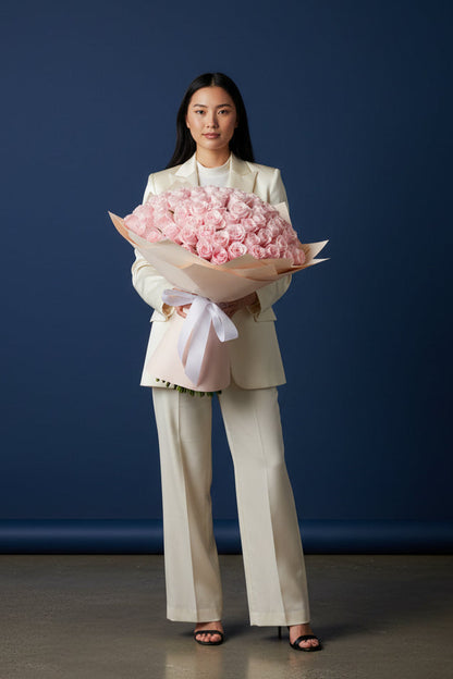 Woman holding a large bouquet of pink flowers against a blue background