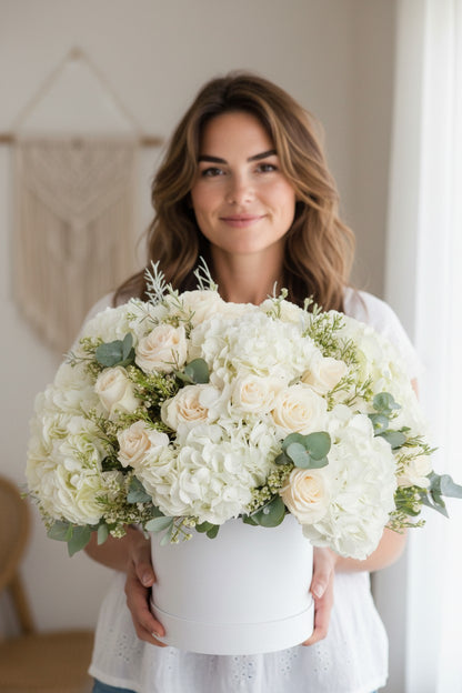 Woman holding a large bouquet of white flowers indoors.