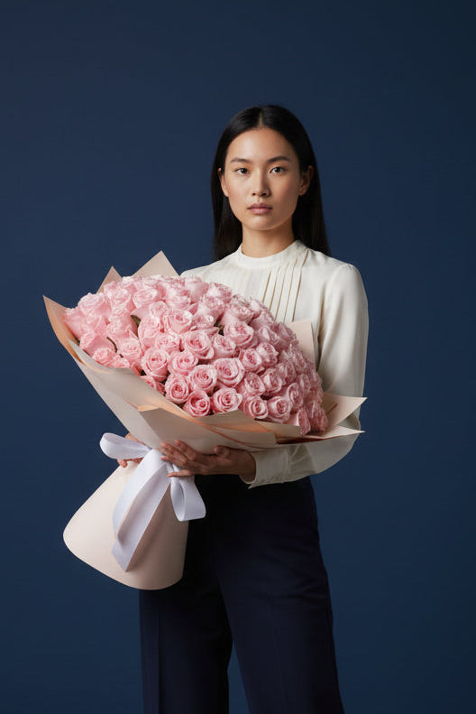 Woman holding a large bouquet of pink roses against a dark background