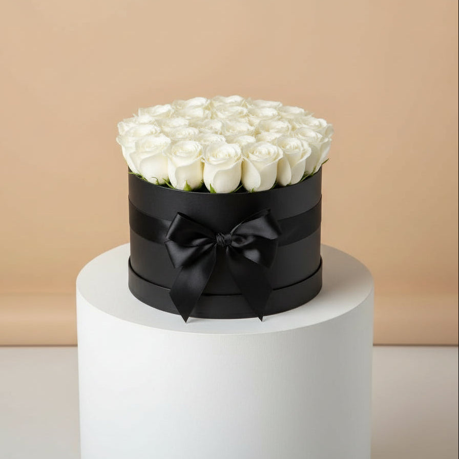 Round black box with white roses and a black bow on a beige background
