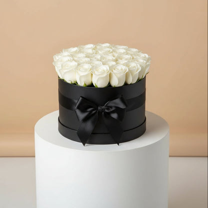Round black box with white roses and a black bow on a beige background