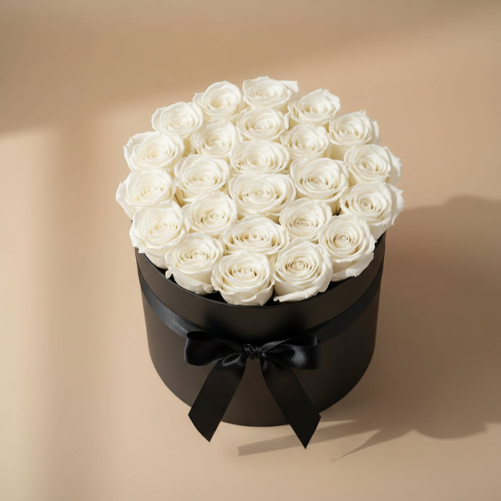 Black round box with white roses and a black bow on a beige background